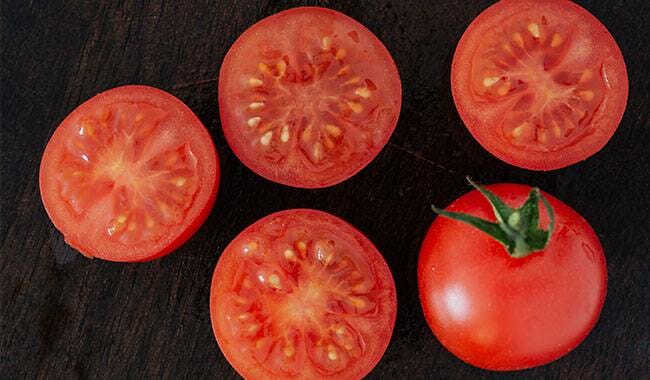 The cut tomato has tomato seeds in the flesh
